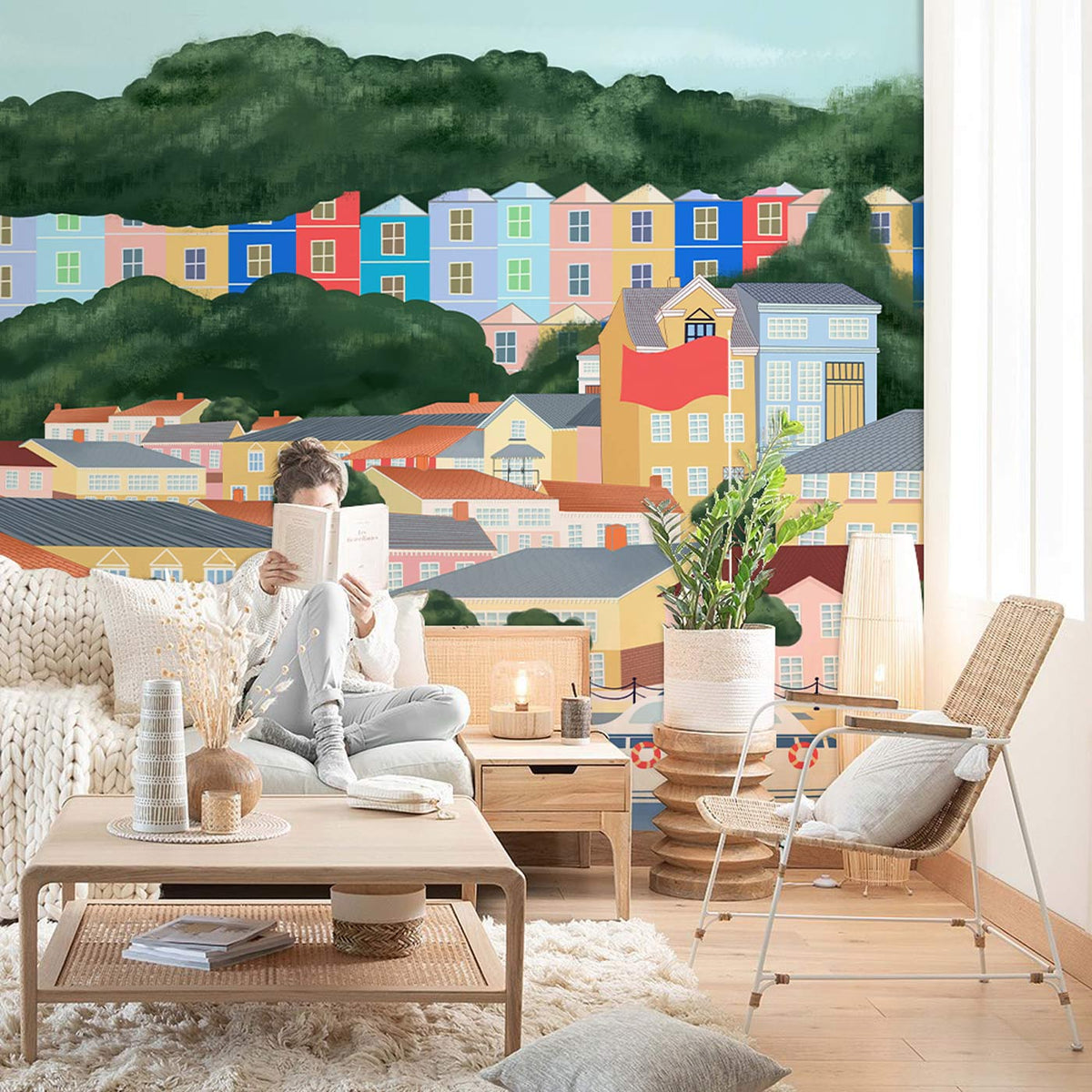 Scenic coastal mural wallpaper; pastel style, wooden flooring, neutral sofa; cosy living room decor.