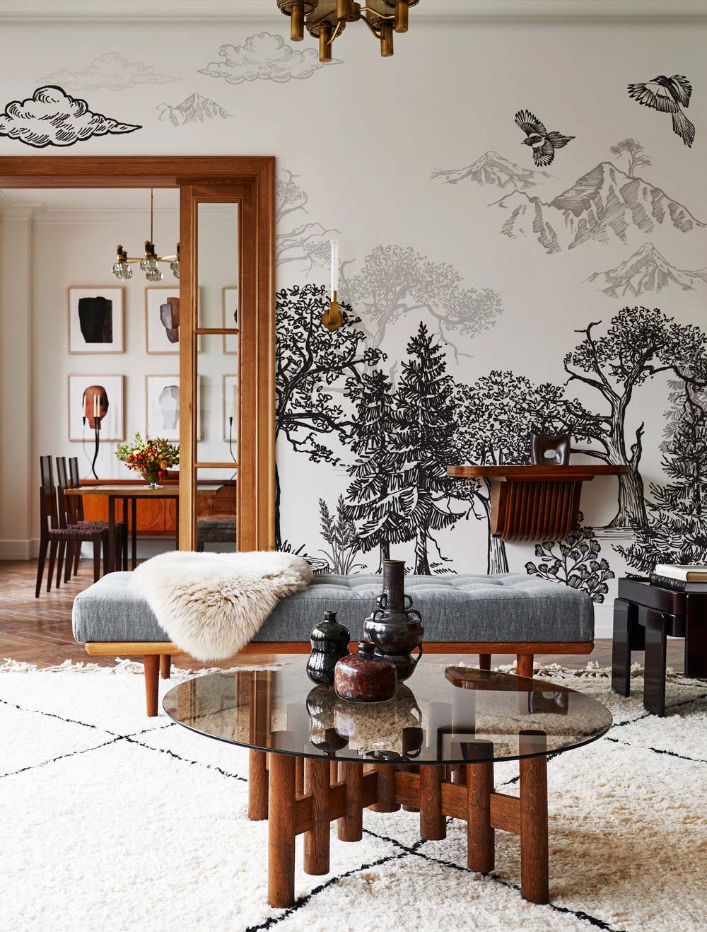 Monochrome woodland mural wallpaper, elegant nature-themed lounge with grey sofa, wooden table, chic design.