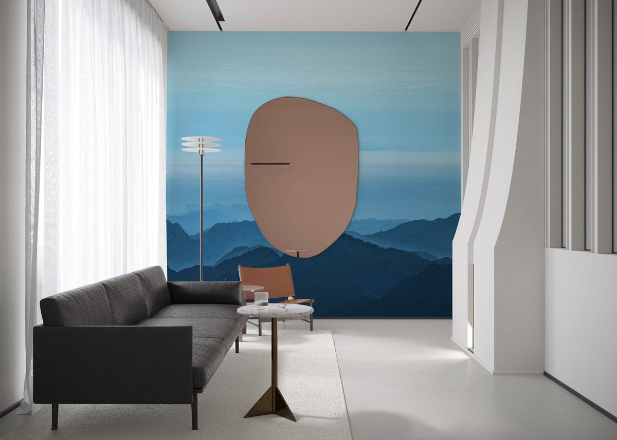 Tranquil blue mountain mural wallpaper, grey sofa, modern lamp, minimalist living room decor, neutral flooring.
