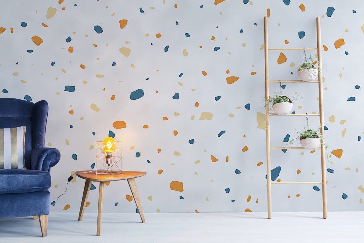 Modern terrazzo wallpaper with orange, navy accents; blue vintage chair, light wood ladder in living room.