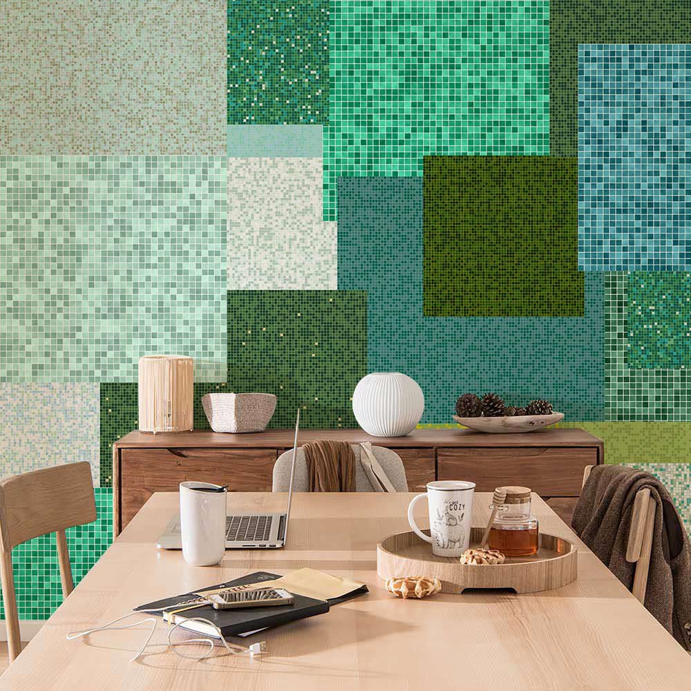 Green geometric patchwork mosaic wall art in modern dining room with wooden table and chairs.