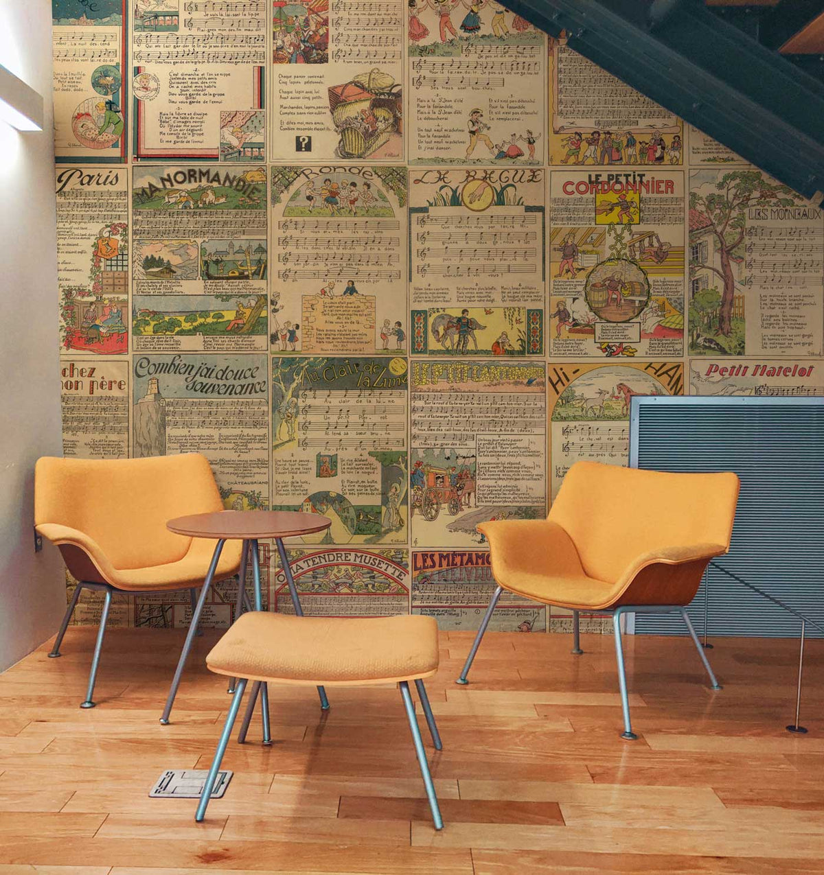 Vintage French collage wallpaper, retro design, orange chairs, wooden floor, cosy room setting.