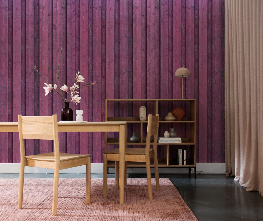 Rustic plum wooden panel wallpaper, dining room with oak furniture, pink rug, bookshelf, vintage decor.