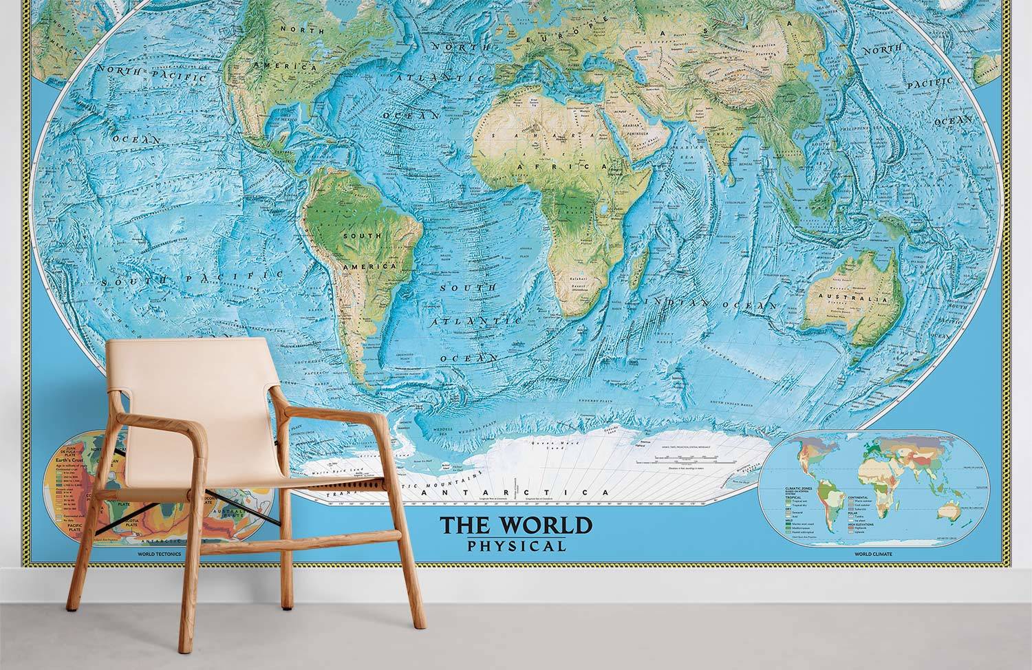 Vintage blue world map mural wallpaper, educational decor, beige chair, white wall in modern room.