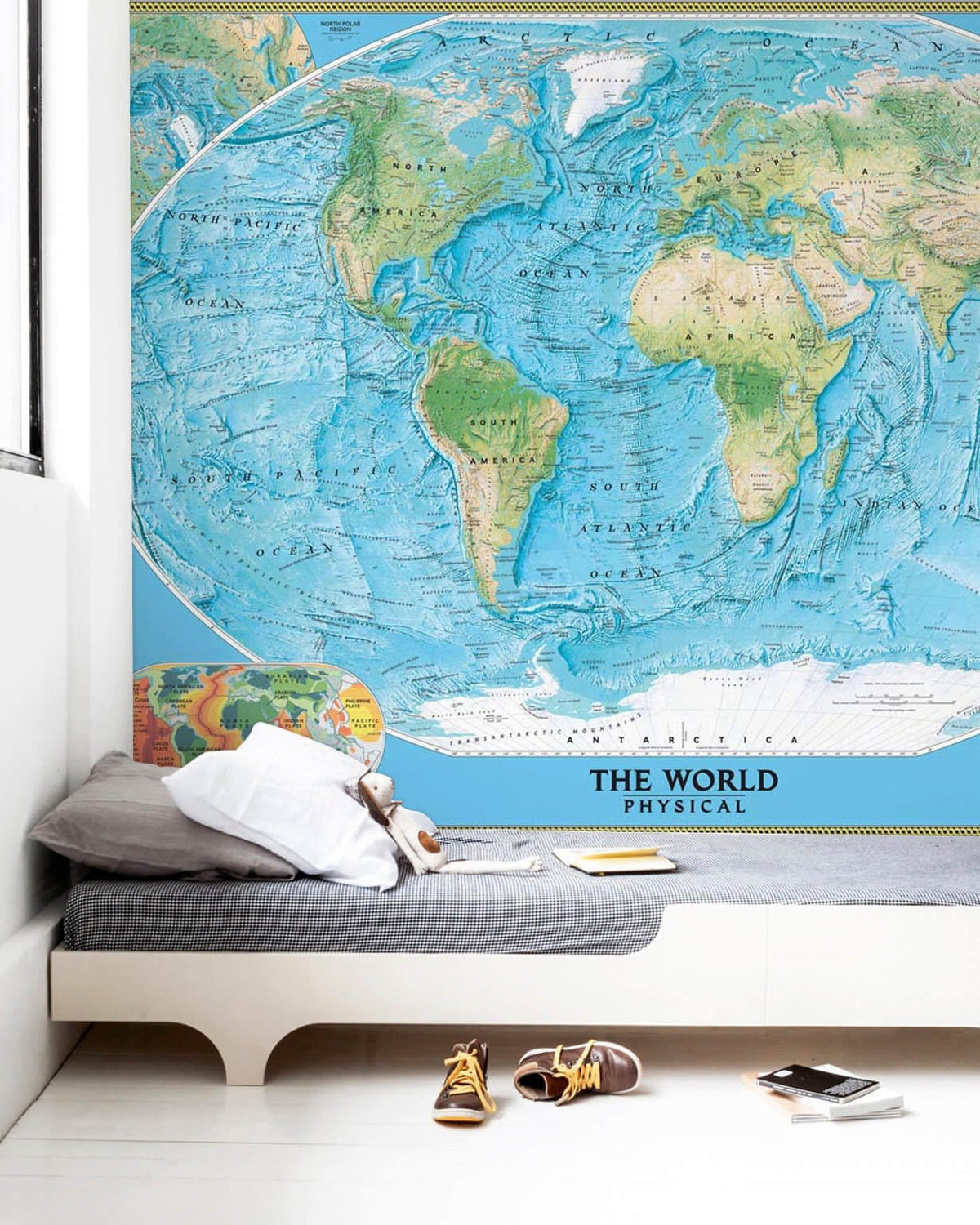 Vintage Blue World Map Mural Wallpaper in modern room with grey sofa, white walls, wooden floor.