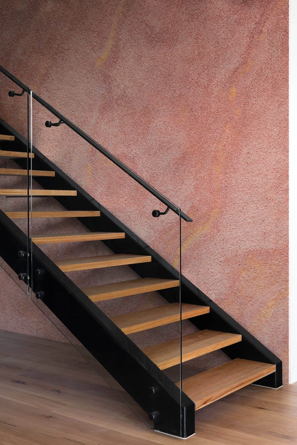 Abstract peach marble textured wallpaper with earthy tones behind modern staircase and wooden flooring.