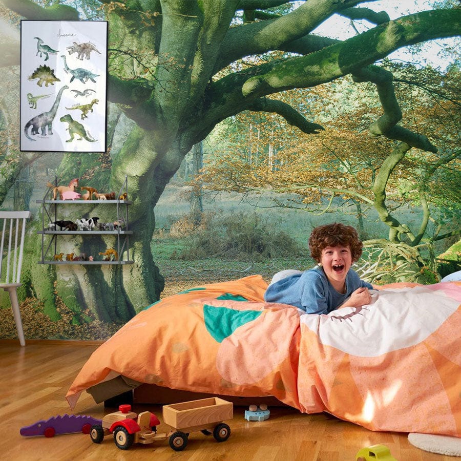 Child's room with Majestic Ancient Oak Forest Mural Wallpaper, wooden floor, dinosaur art, cosy duvet.