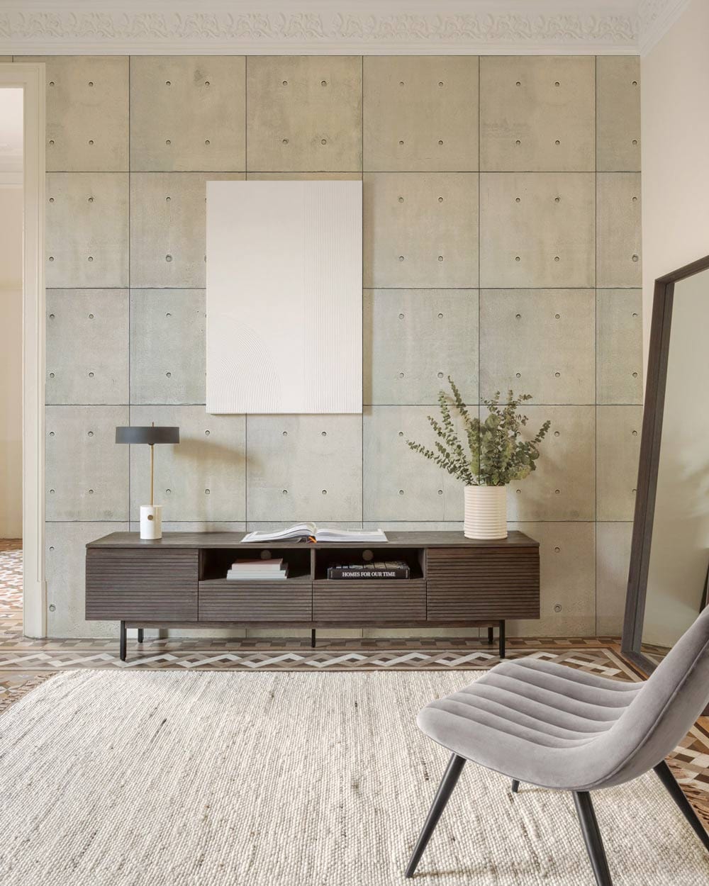 Modern Industrial Grey Concrete Effect Wallpaper, living room setting with grey chair, patterned flooring.