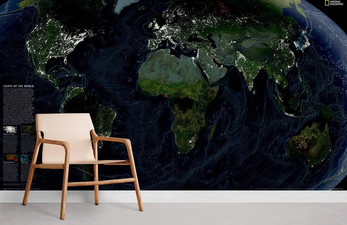 Illuminated Earth wallpaper mural with modern wooden chair, grey flooring, and vibrant night world map.