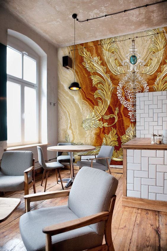 Ornate Gold Baroque mural wallpaper, neutral chairs, wooden flooring, modern lights in stylish living area.