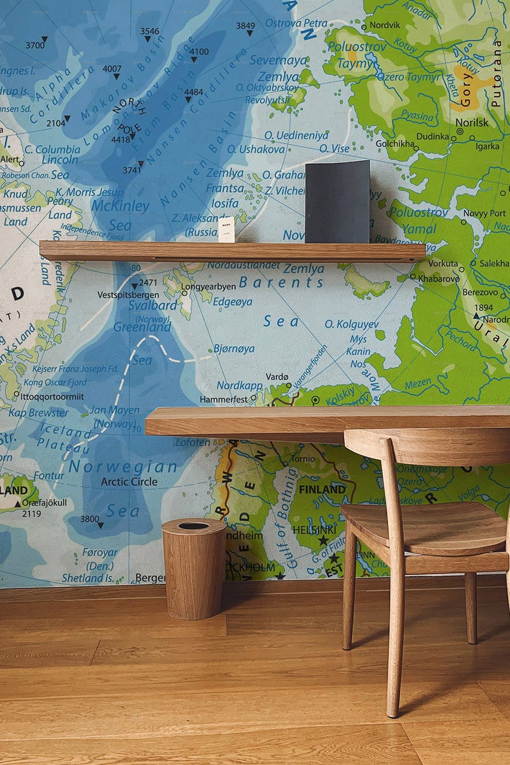 Vintage Nordic Map Mural Wallpaper in blue-green tones, wooden table and chair, oak flooring.