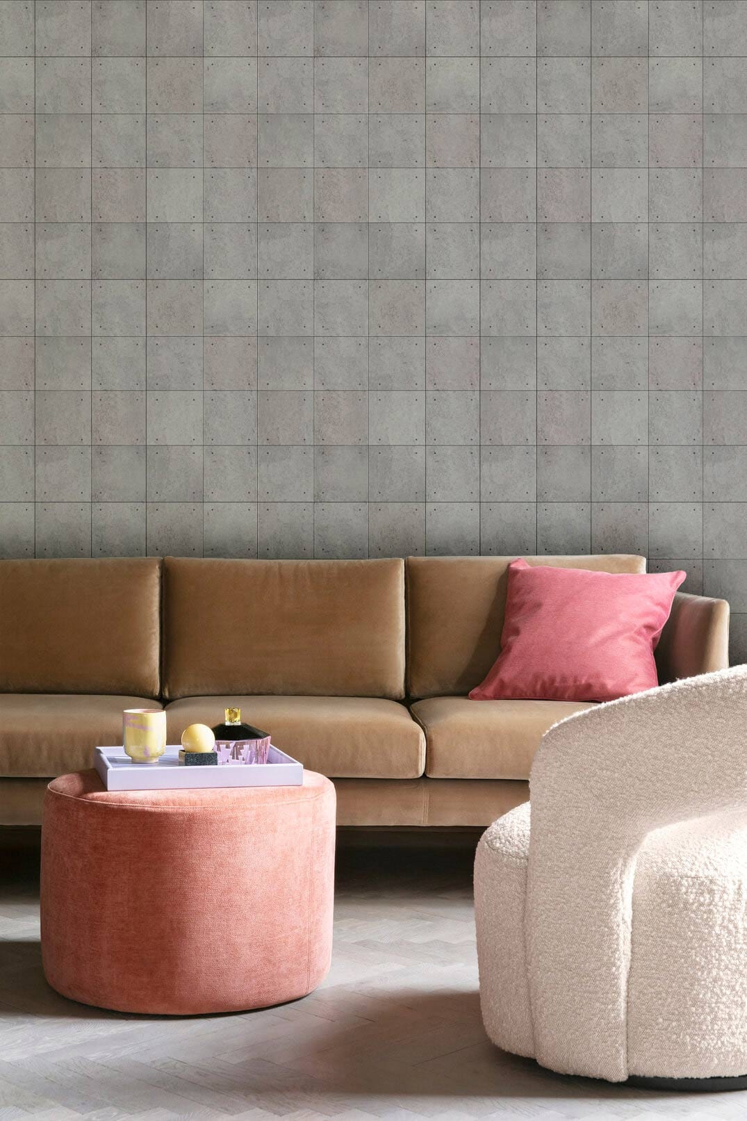 Contemporary grey stone wallpaper in modern living room with tan sofa, pink ottoman, and white chair.