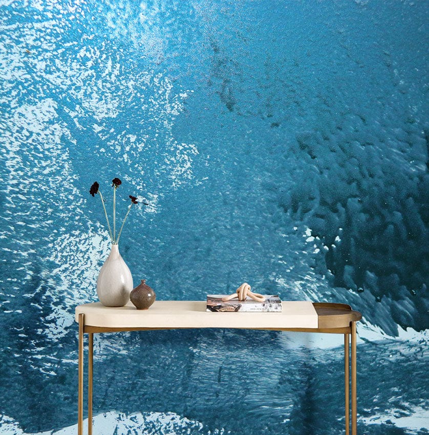 Teal ocean wave mural wallpaper in modern interior with minimalist table and textured surface design.