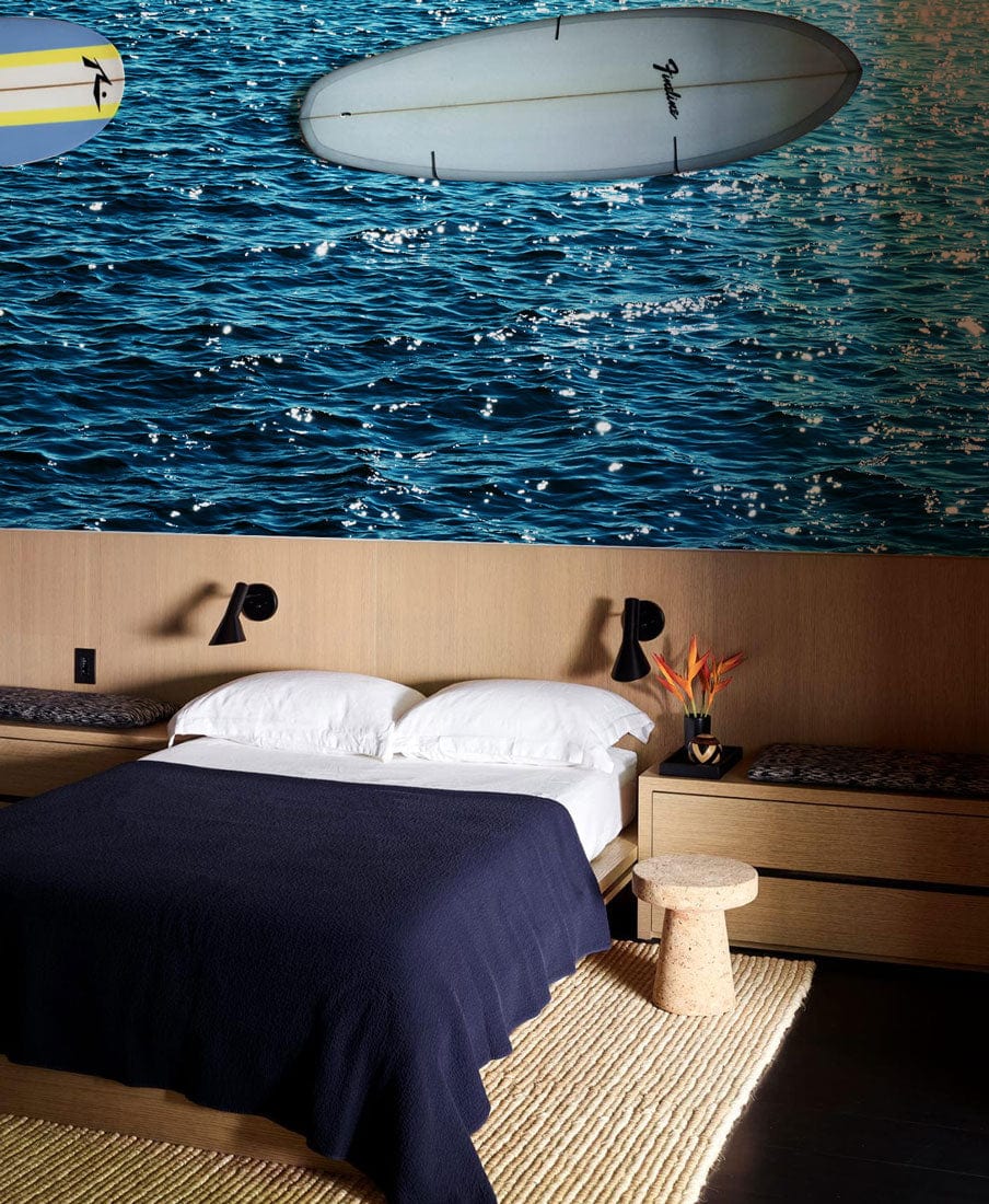 Tranquil Ocean Blue Ripple wallpaper in a calm bedroom with wooden panelling, dark bedding, and rug.