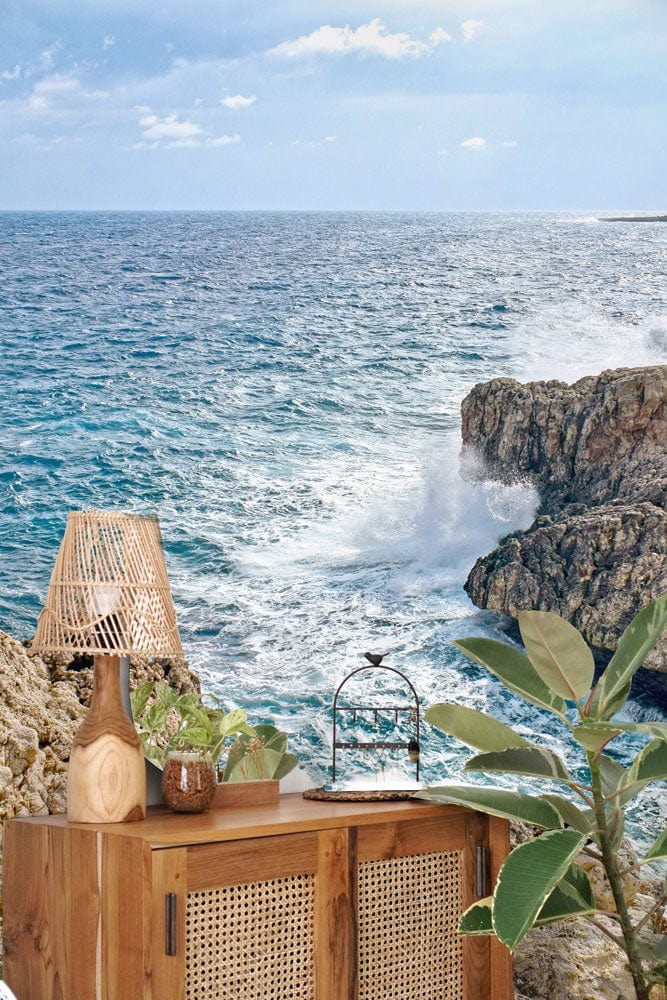 Coastal Cliff Serenity mural wallpaper featuring ocean waves and rocks, wooden cabinet and natural decor.