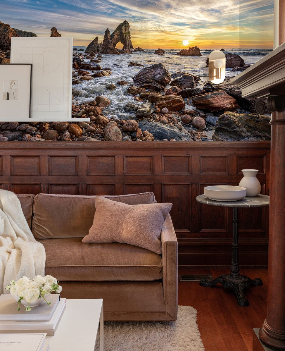 Sunset Coastal Landscape Mural Wallpaper, dramatic rocks, brown sofa, wooden panelling, cosy living room.