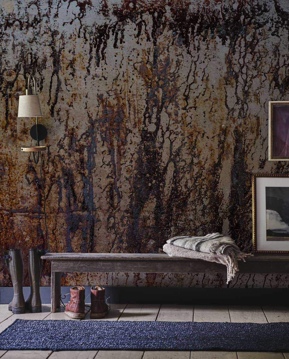 Rustic industrial wallpaper complements dark wooden bench, blue rug, textured flooring, earthy decor in hallway.