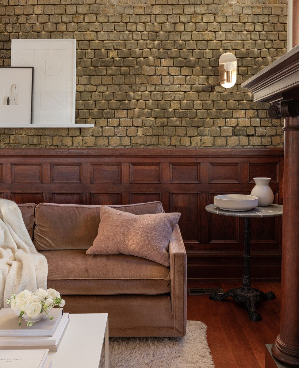 Rustic stone wallpaper, earthy tones, brown sofa, wooden panelling, elegant living room decor.