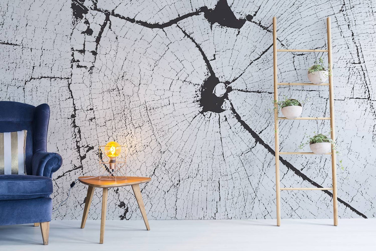 Monochrome tree trunk wallpaper mural with blue velvet sofa, wooden table, ladder shelf in living room.