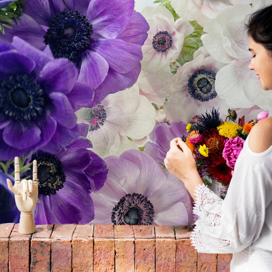 Elegant purple and white anemone mural wallpaper, modern interiors, brick pattern, woman arranging flowers.