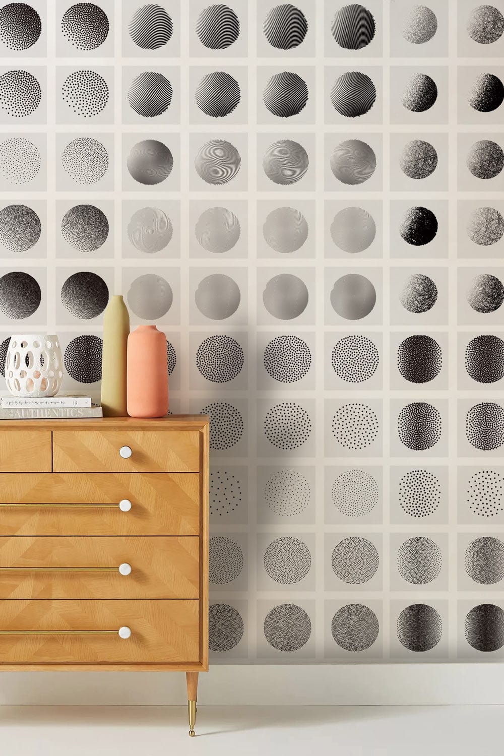 Monochrome geometric circles wallpaper with wooden dresser, modern minimalist decor, living room setting.