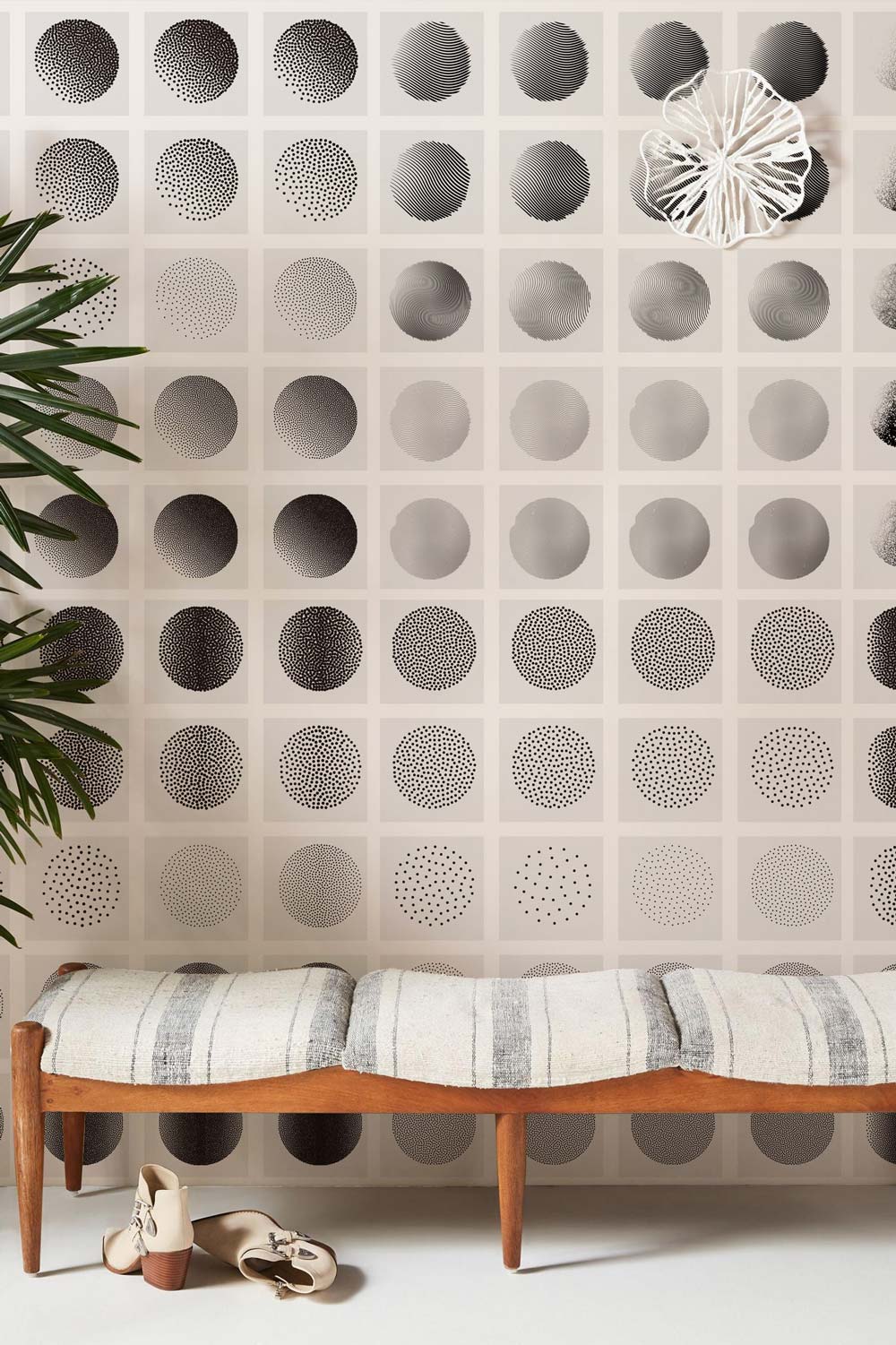 Monochrome geometric wallpaper mural in modern room with wooden bench and striped cushion.