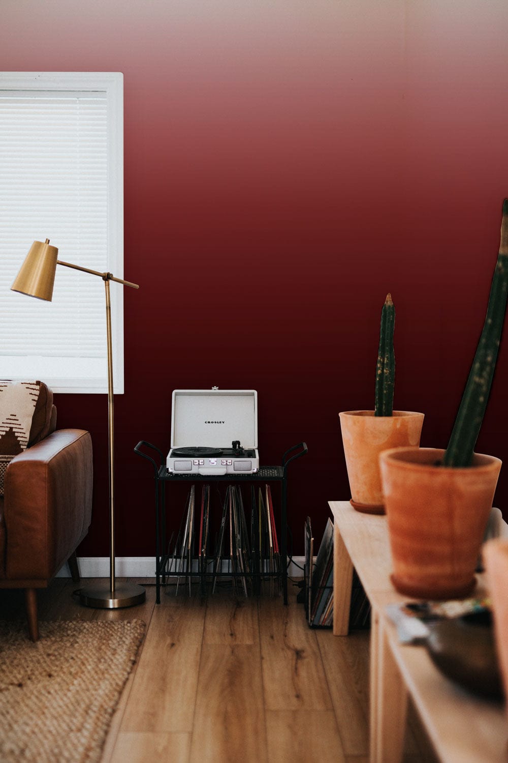 Elegant red gradient wallpaper in modern living room with brown sofa, wooden flooring, and floor lamp.