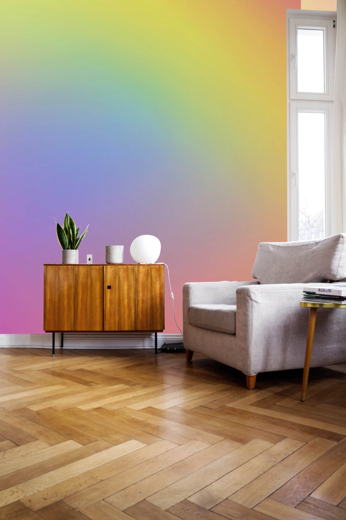 Bright living room with a Pastel Dreamscape Gradient Mural Wallpaper, mid-century cabinet, beige armchair, wooden floor.