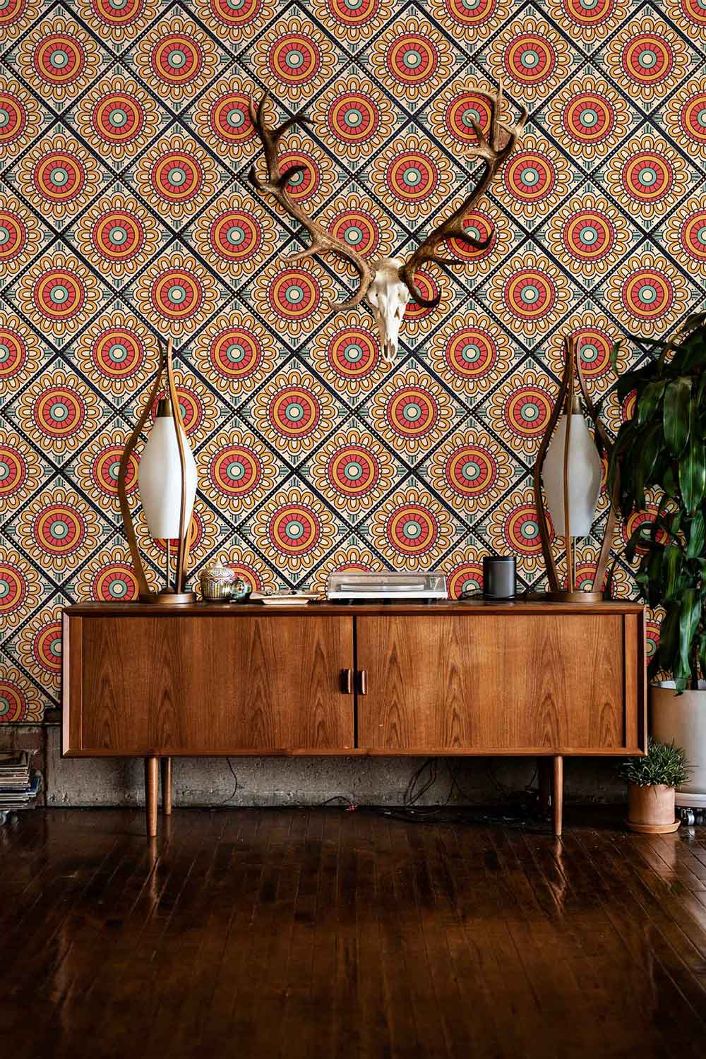 Retro geometric floral wallpaper, vibrant red and yellow, with wooden sideboard, mirrors, and dark wood flooring.