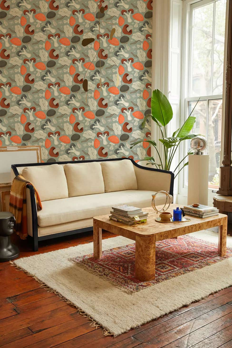 Vintage mushroom motif wallpaper with earthy tones, beige sofa, rustic wooden floor, living room decor.
