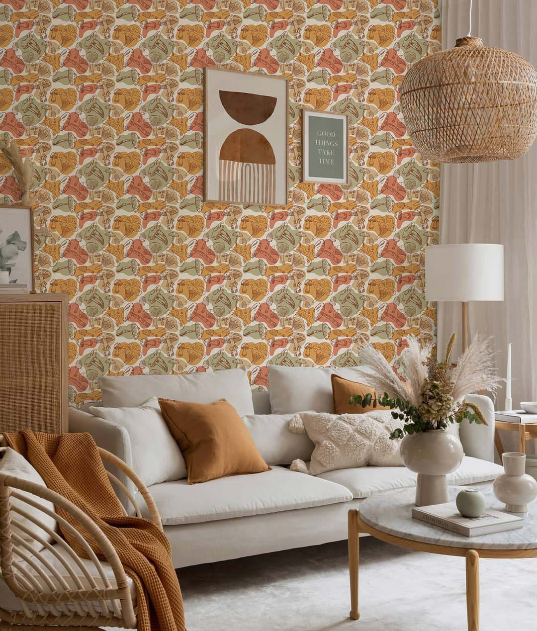 Autumnal leaf motif wallpaper in a living room with beige sofa, wicker pendant light, and rug.