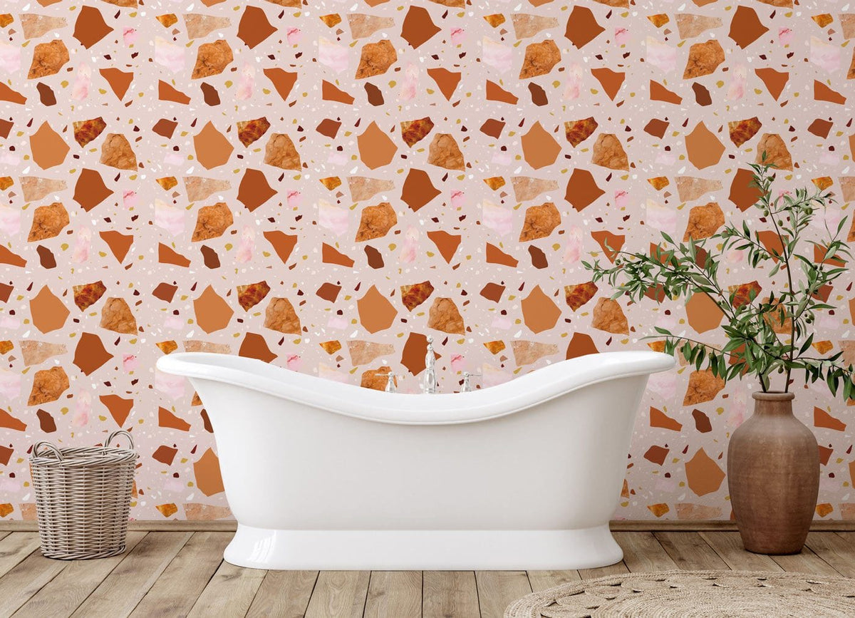 Terracotta and blush terrazzo wallpaper in bathroom with white freestanding bath and wooden flooring.