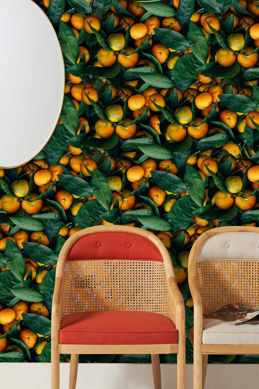 Citrus Orchard Leaf Wallpaper with orange rattan chairs and round mirror in living room setting.
