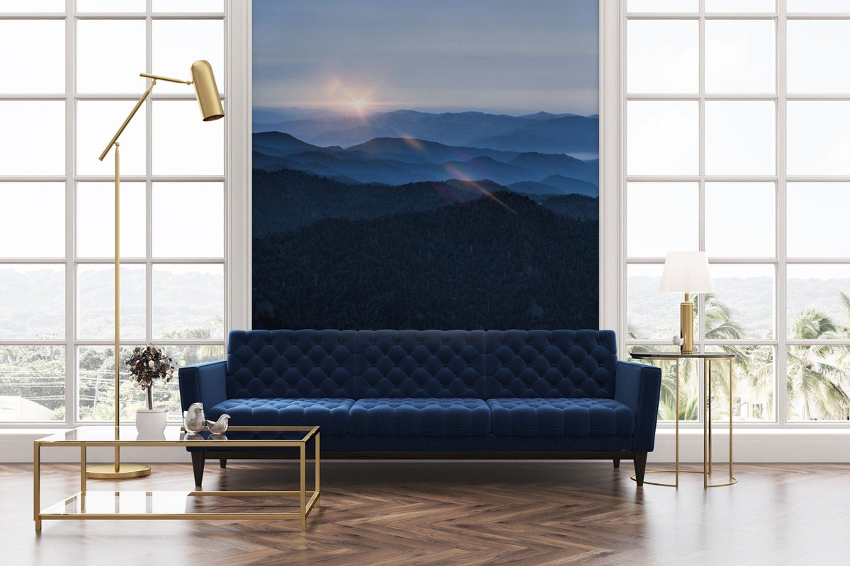 Blue Mountain Sunrise mural wallpaper in living room with blue sofa, gold lamp, parquet flooring.