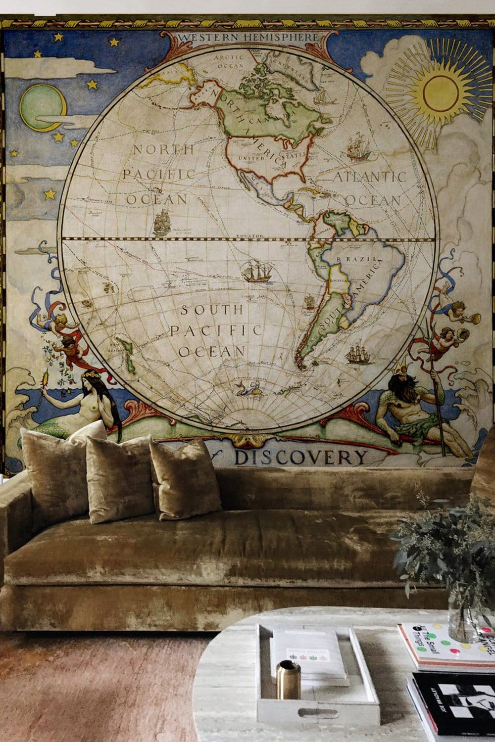 Vintage World Map Mural in antique nautical style, earthy tones, with velvet sofa and wooden flooring.