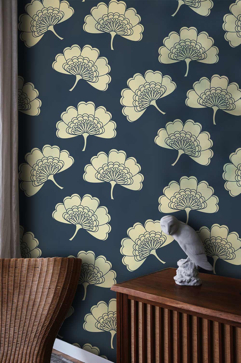 Navy and cream floral wallpaper in vintage style with dark wooden cabinet, wicker chair, and sculpture.