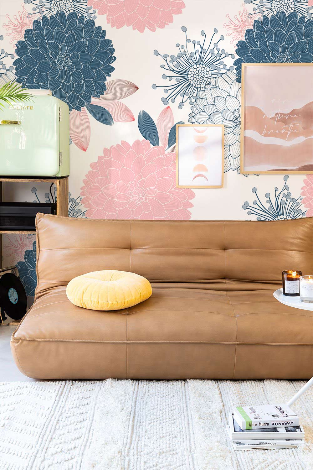 Elegant floral wallpaper, chic interior with brown leather sofa, art pieces, light flooring, modern decor.