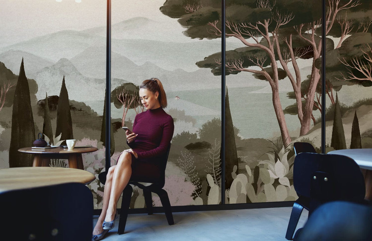 Serene woodland mural in greens, earthy tones; woman seated, modern chairs, café setting, light flooring.