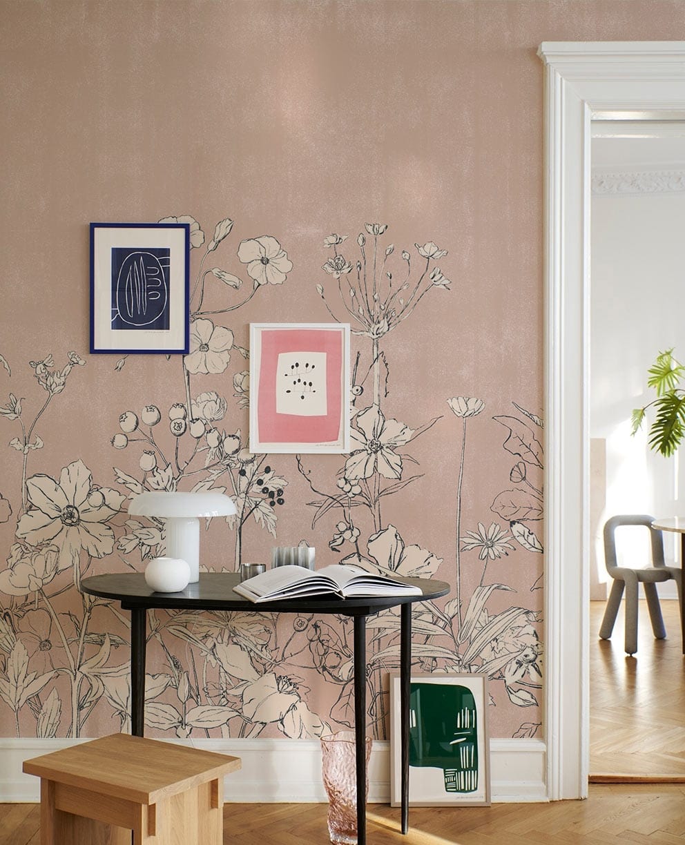 Blush Pink Floral Mural Wallpaper with Botanical Sketch, small black table, wooden stool, herringbone flooring.