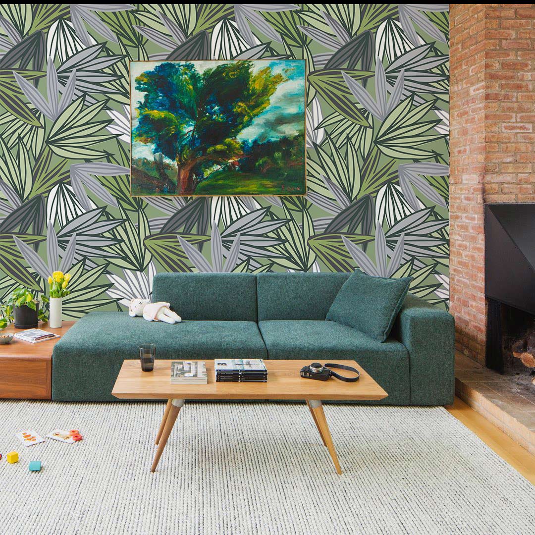 Green geometric botanical wallpaper mural, with a grey and green sofa, wooden table, in a modern lounge.