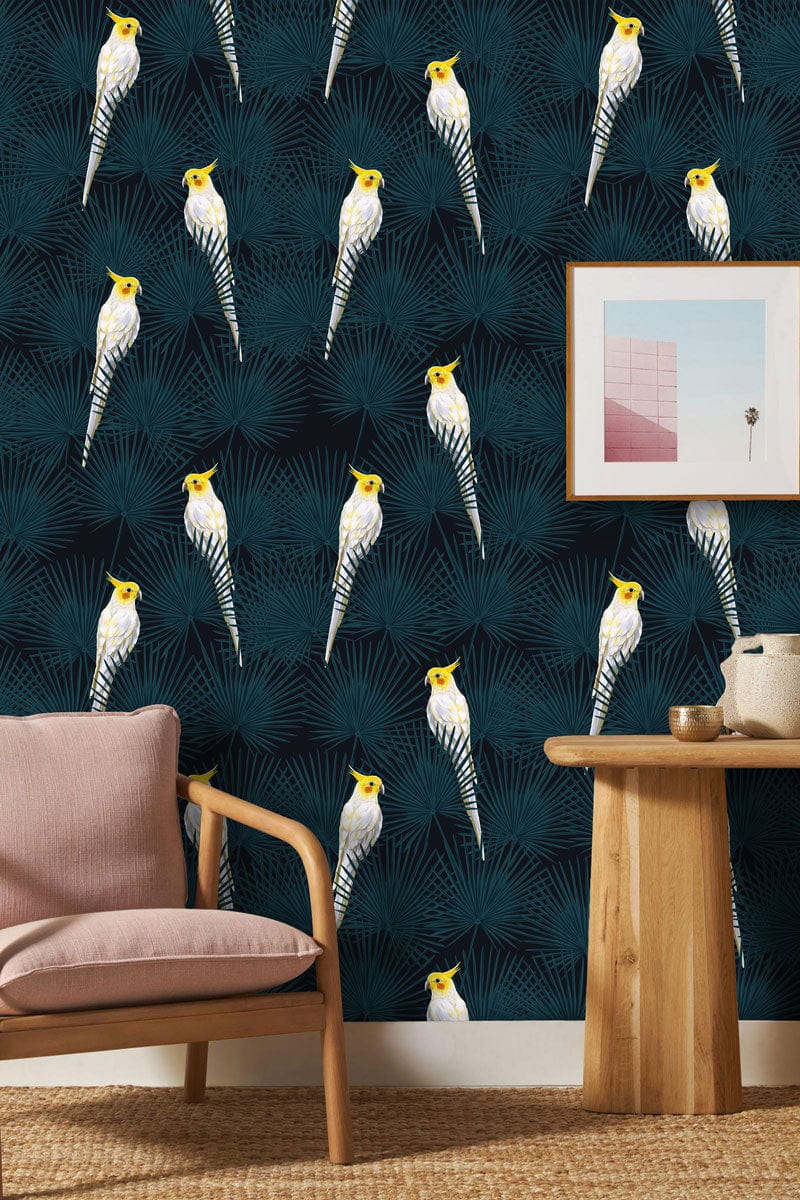 Tropical Cockatoo Pattern Wallpaper in teal, paired with a pink fabric armchair and wooden table.