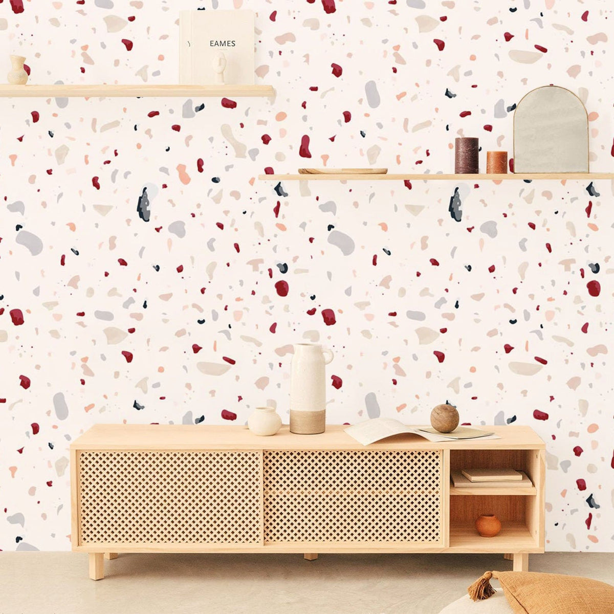 Modern terrazzo wallpaper in cream and red with wooden shelves, sideboard, light flooring in living room.