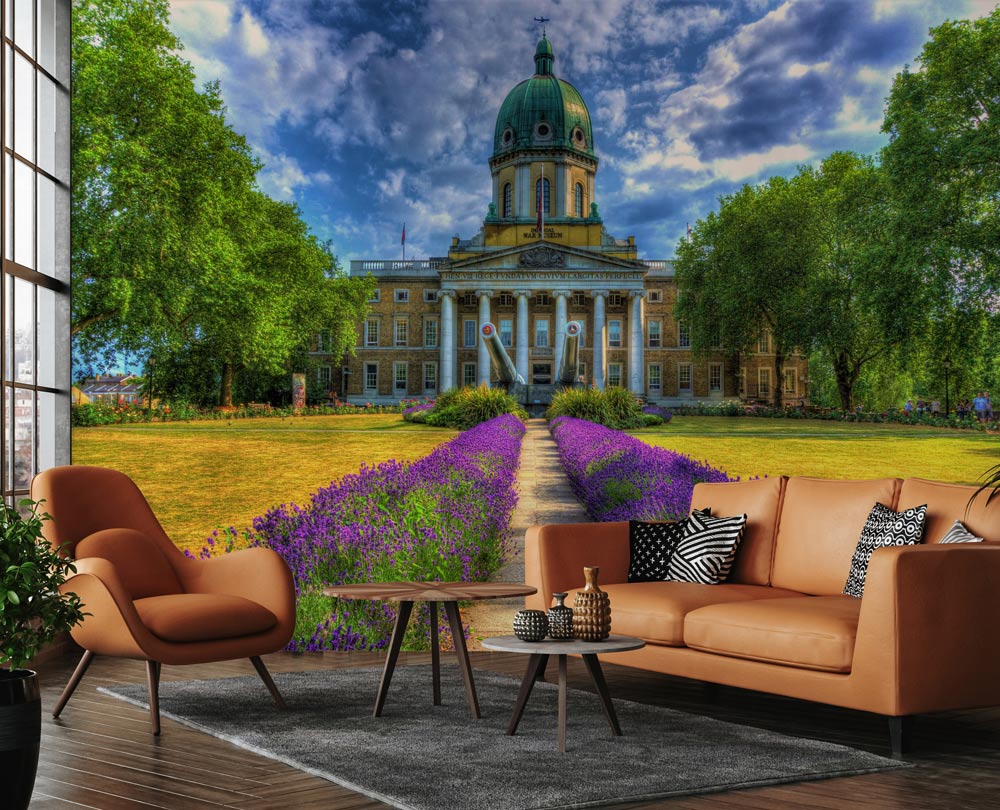 Historic Garden Pathway mural wallpaper with lavenders, brown sofa, wooden flooring, and scenic architecture.