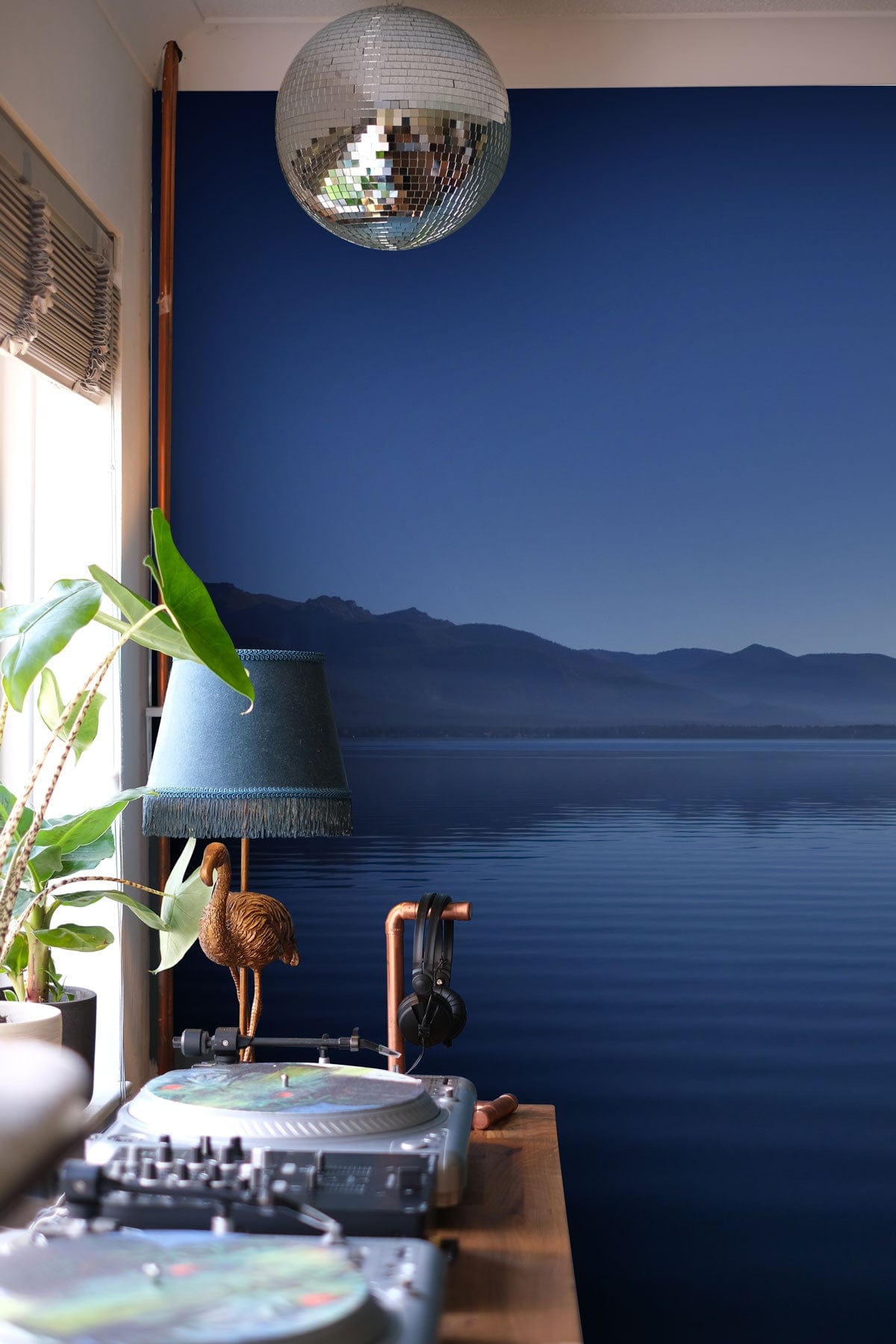 Panoramic serene blue lake wallpaper with disco ball, desk, and stylish interior decor elements.