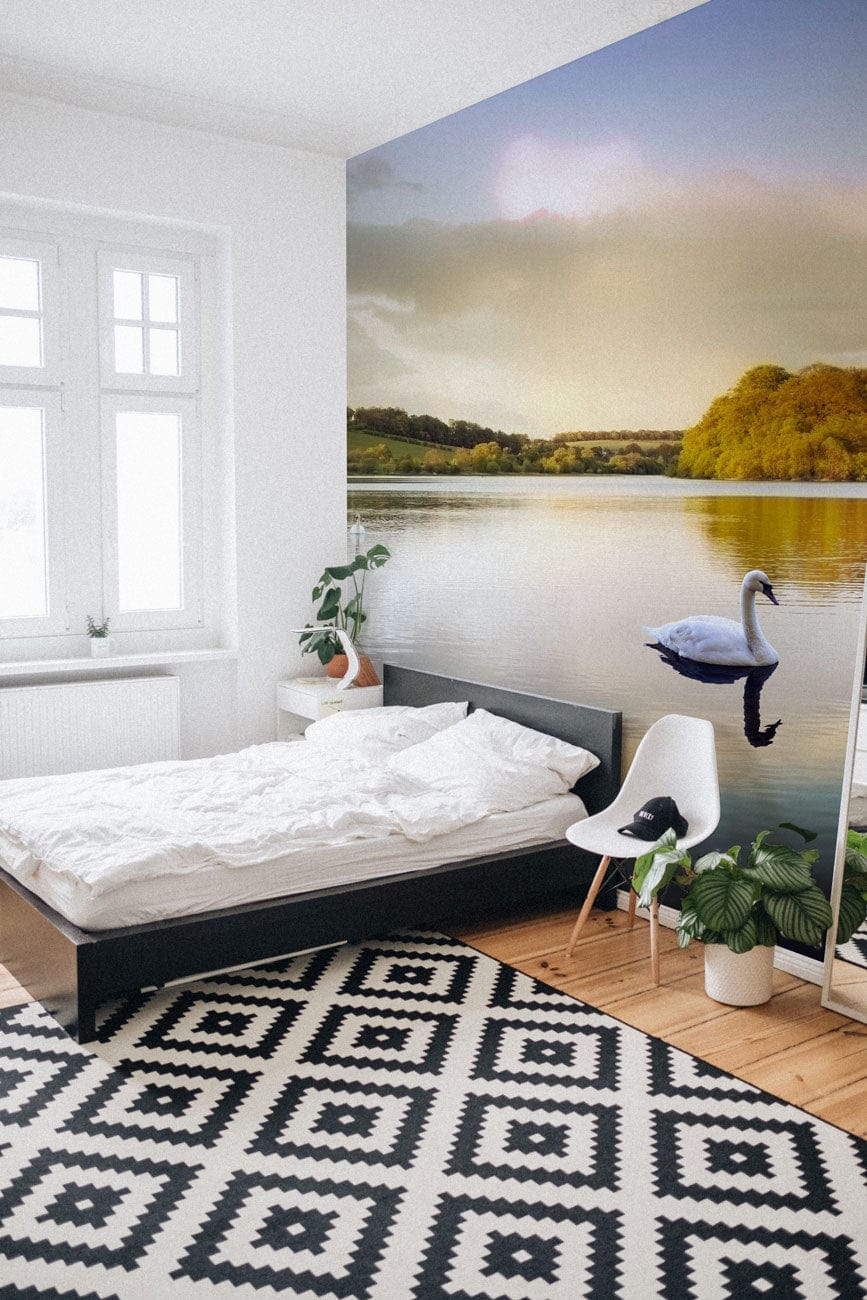Tranquil Lakeside View wallpaper in bedroom, black bed, white chair, geometric rug, wooden flooring.