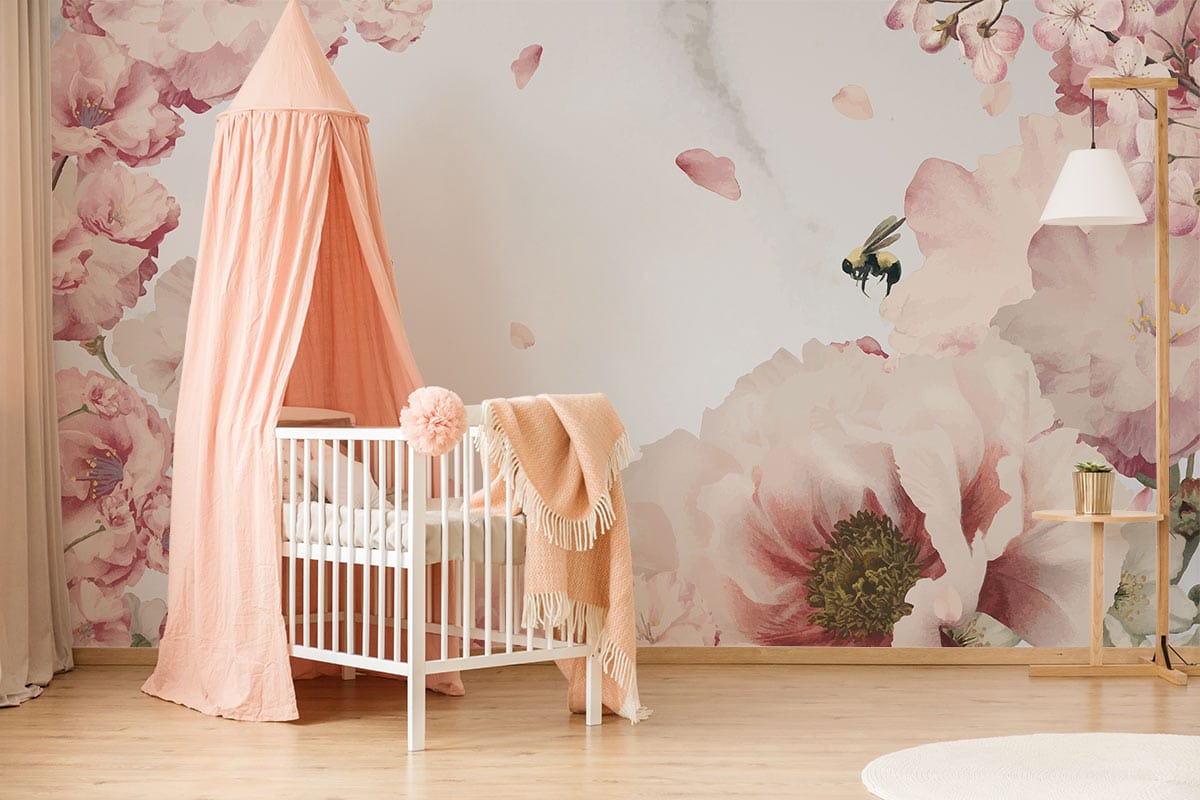 Pink floral wallpaper with bee design, nursery decor, wooden floors, white cot, peach canopy.