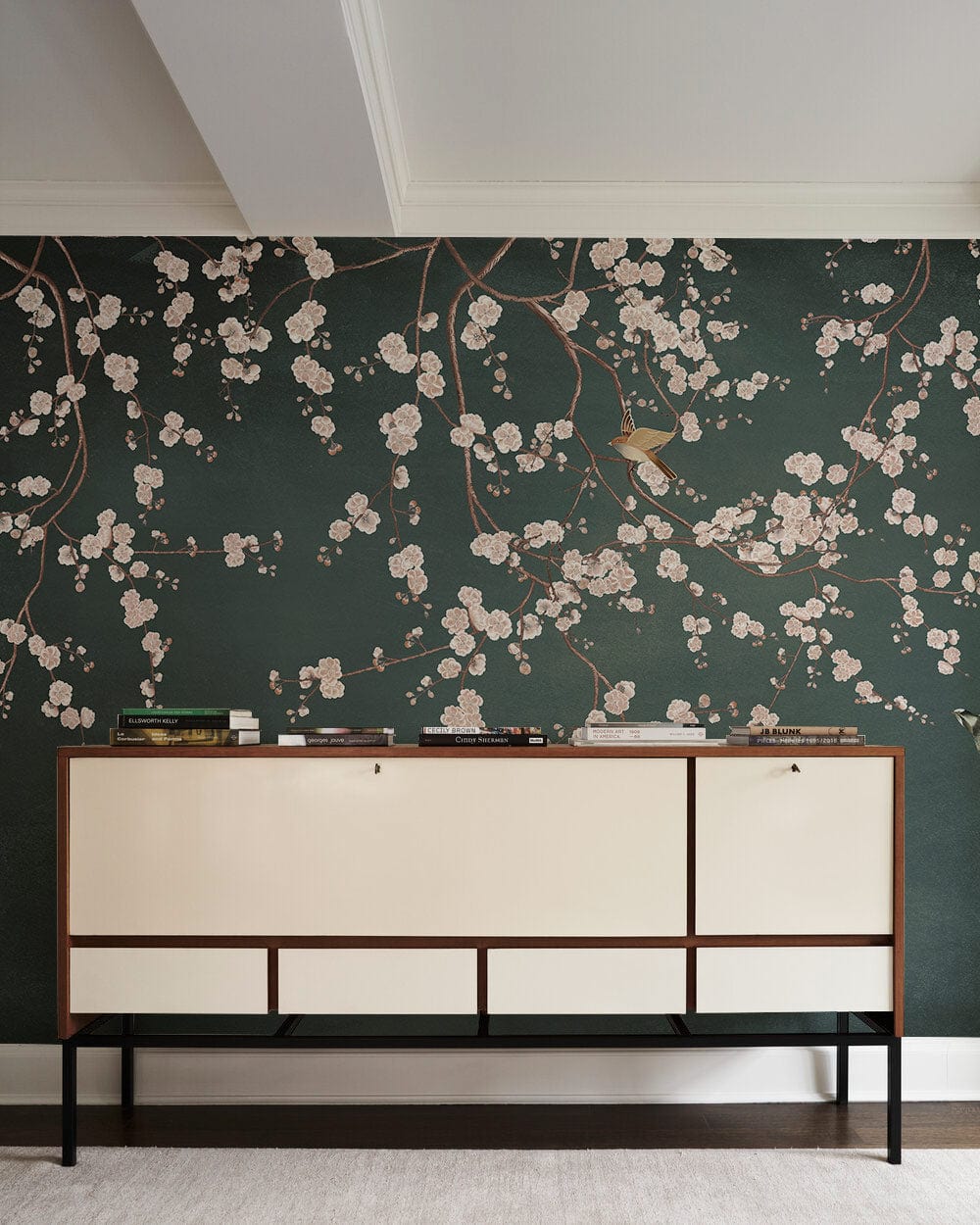 Elegant dark green floral mural wallpaper in modern bedroom with cream sideboard and white ceiling.