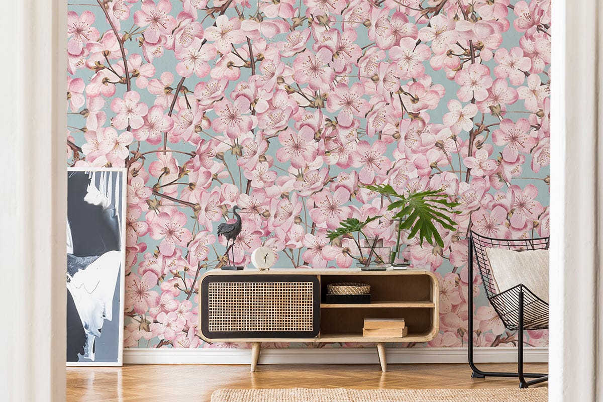 Elegant cherry blossom wallpaper, soft pink and blue tones, mid-century sideboard, modern wicker chair.
