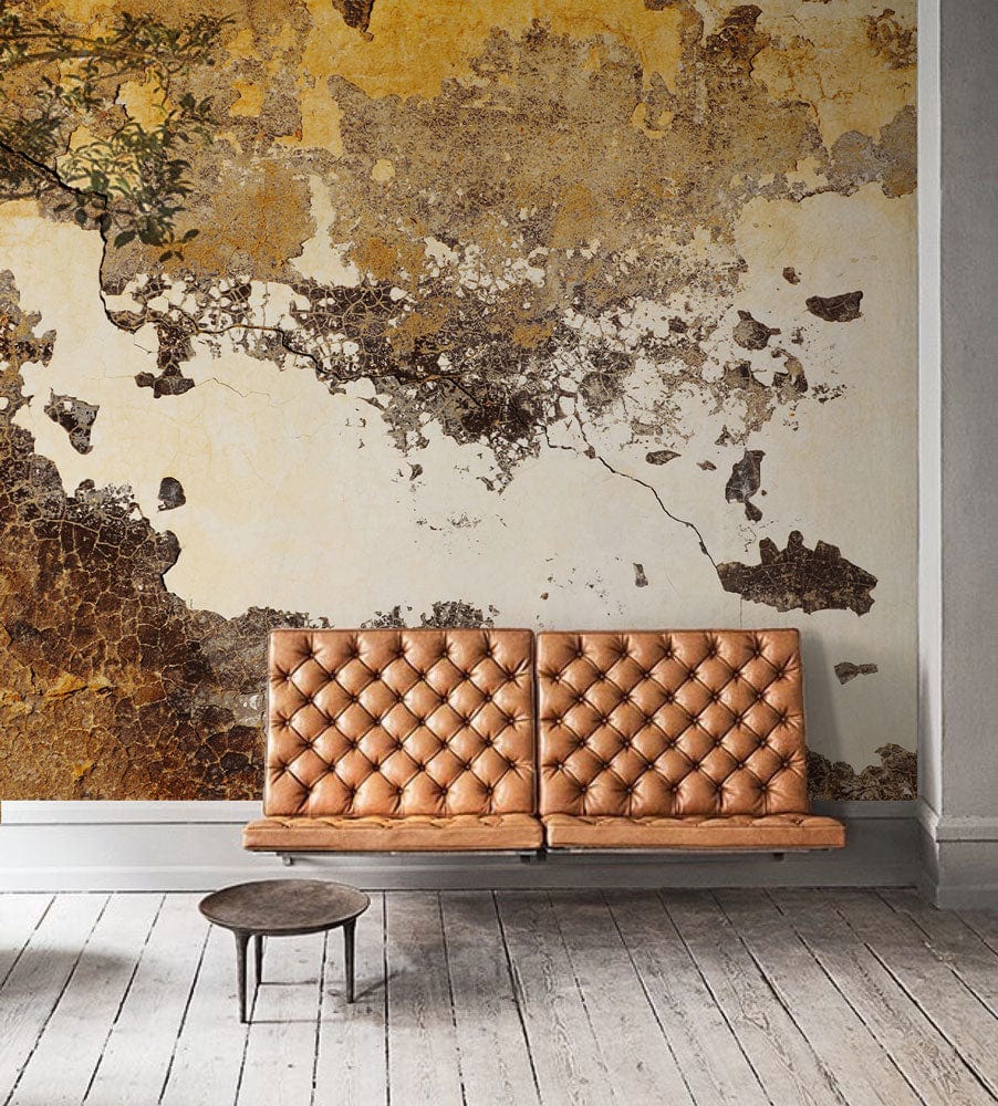 Rustic Industrial aged patina wallpaper, tufted camel sofa, distressed wood flooring, warm earthy decor.