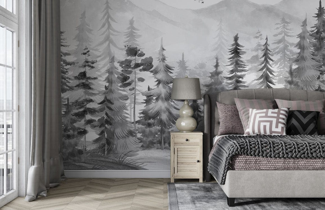 Monochrome forest mural wallpaper in bedroom with grey bed, cushion set, lamp, and chevron wood flooring.